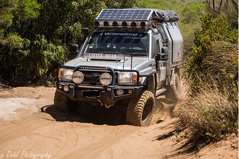 a 4WD car driving down a dirt hill with Aluminium Roof Racks